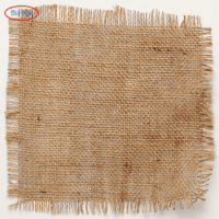 在灯光明亮的仓库里，一张质朴的木桌上摆放着一大卷紧密编织的天然棕色粗麻布，展示了用于大批量粗麻布订单的高强度黄麻纤维。